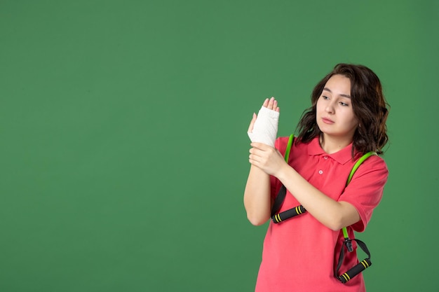 녹색 배경 작업 부상 건강 유니폼 병원 색상 통증 작업에 그녀의 다친 손에 붕대와 전면보기 젊은 판매원