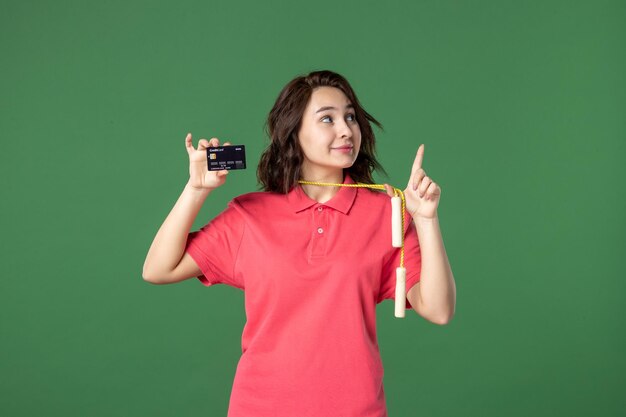 Front view young saleswoman with skipping rope holding bank card on green surface