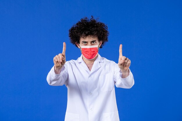 파란색 배경 약물 백신 건강 covid-대유행 의학 병원 바이러스에 빨간색 마스크와 의료 소송에서 전면 보기 젊은 심각한 의사