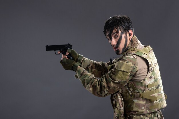 Front view of young soldier in camouflage aiming gun on dark floor palestine tank war