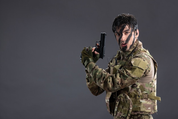 Free photo front view young soldier fighting in camouflage with gun on the dark wall