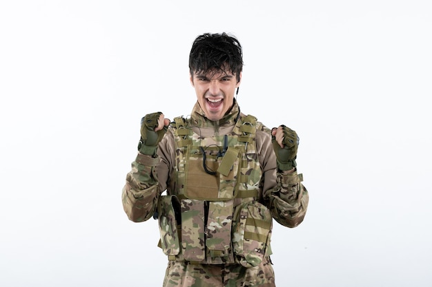 Front view of young soldier in military uniform on white wall