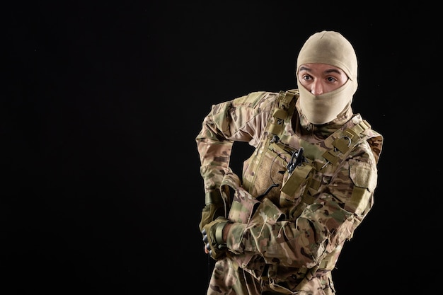 黒い壁に銃を持った制服を着た若い兵士の正面図