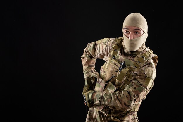 Front view young soldier in uniform with gun black wall