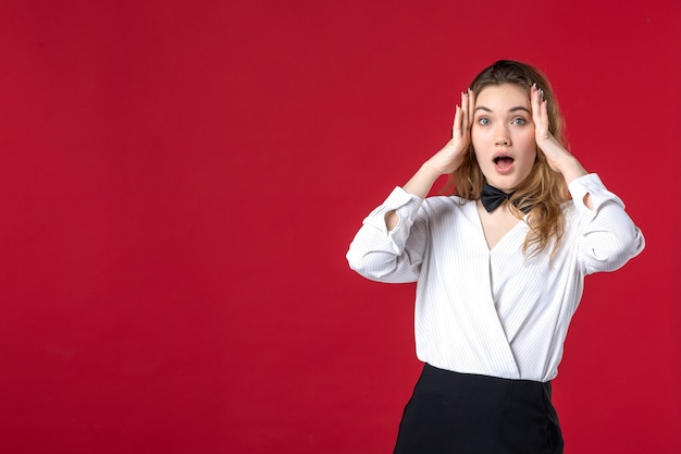 Front view of young surprised waitress woman butterfly on the neck on red background