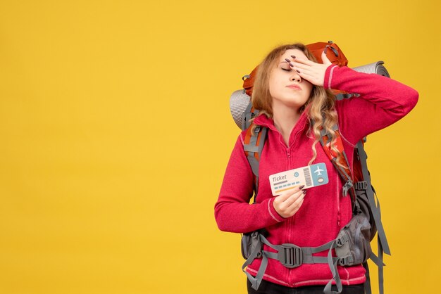 Front view of young tired travelling girl in medical mask holding ticket