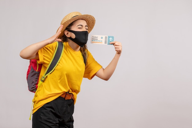 Front view young traveller with backpack holding up ticket closing eyes