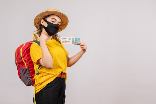 Front view young traveller with backpack holding up ticket making thumbs up