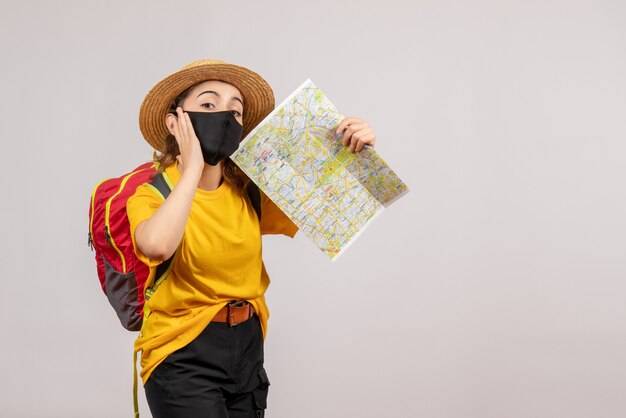 Front view young traveller with red backpack holding up map