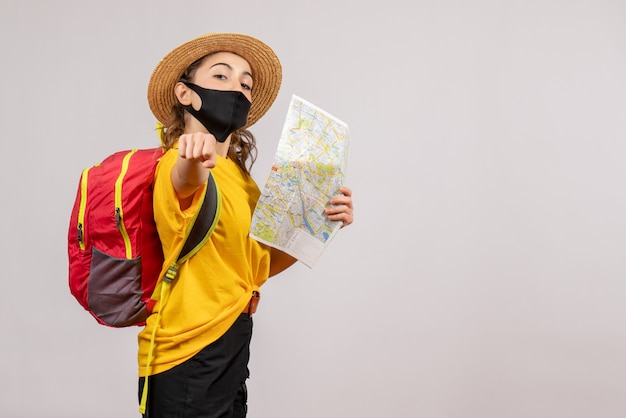 地図を持って赤いバックパックを持つ正面の若い旅行者