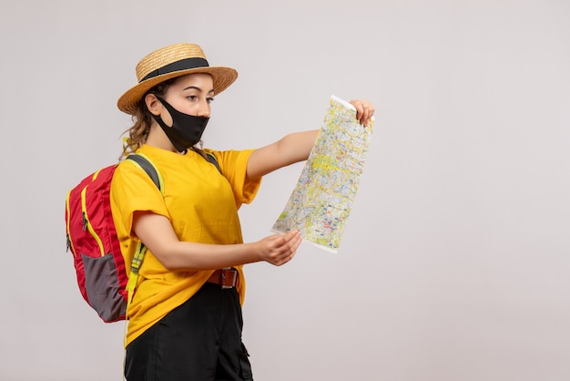 Вид спереди молодой путешественник с красным рюкзаком, глядя на карту