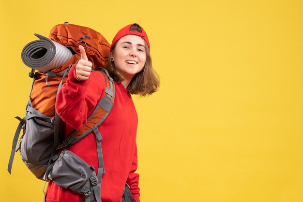 Front view young traveller woman in red backpack giving thumb up