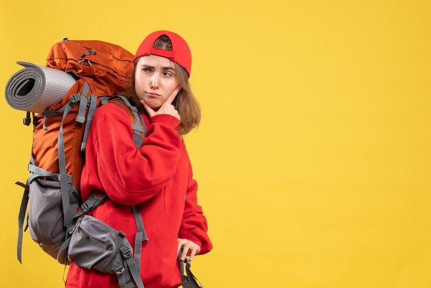 彼女のあごに手を置いている赤いバックパックの正面図若い旅行者の女性