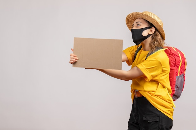 Front view young traveller woman with backpack holding cardboard