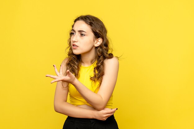 Front view of young woman arguing on a yellow wall