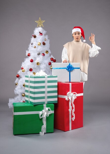 Front view young woman around holiday presents on grey floor new year christmas gift