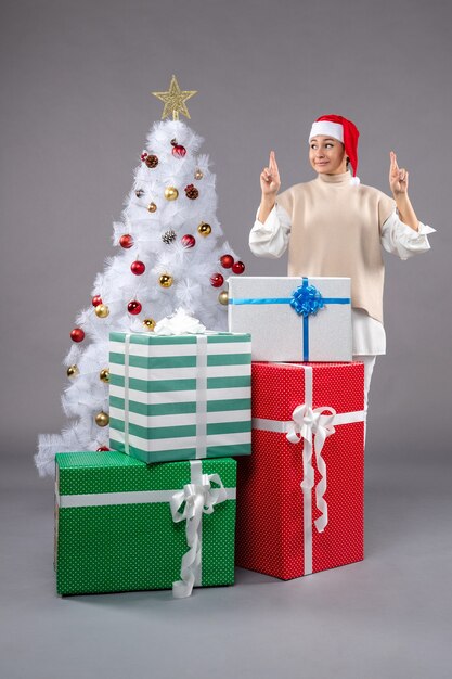 Front view young woman around holiday presents on a grey 