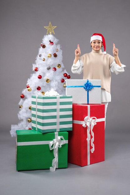 Front view young woman around holiday presents on grey 