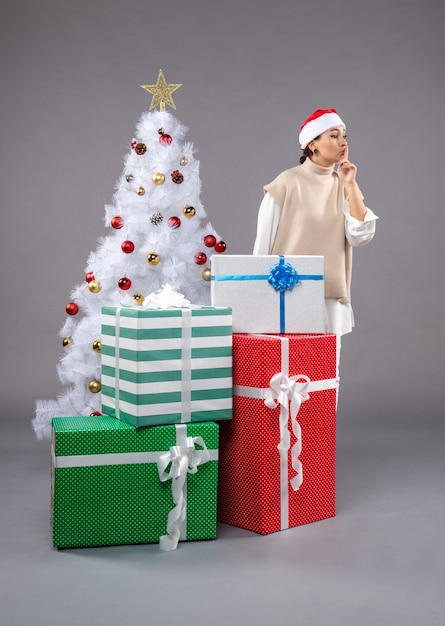 Front view young woman around holiday presents on grey 