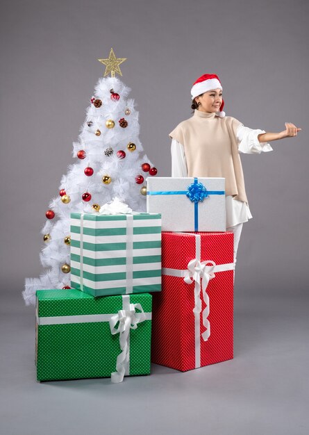 Front view young woman around holiday presents on grey 
