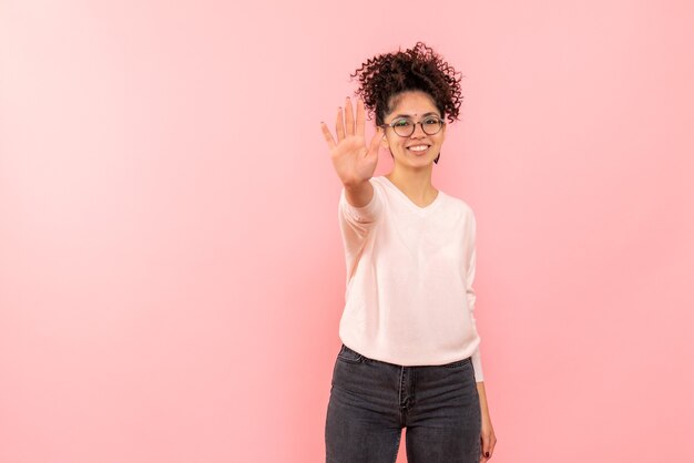 Front view of young woman asking to stop with smile on pink wall