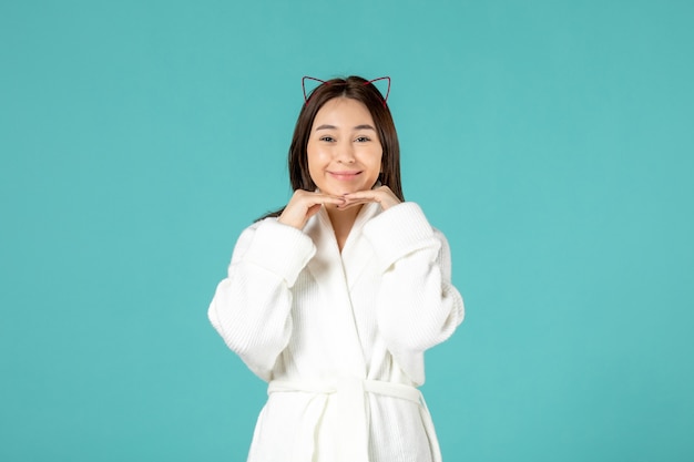 front view of young woman in bathrobe on blue wall