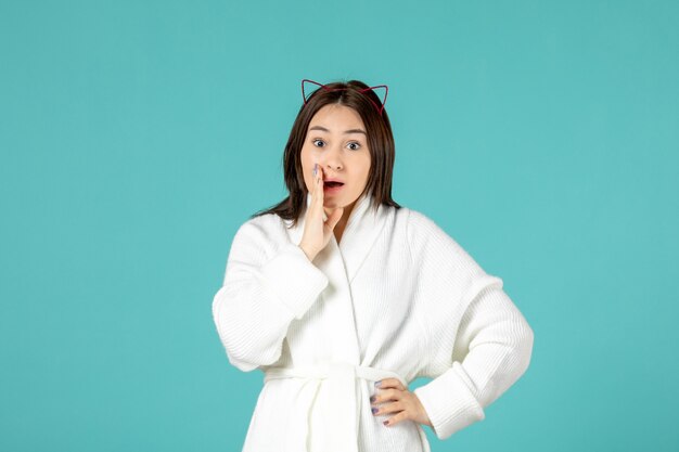 front view of young woman in bathrobe on blue wall