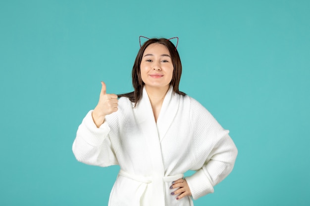 front view of young woman in bathrobe on blue wall