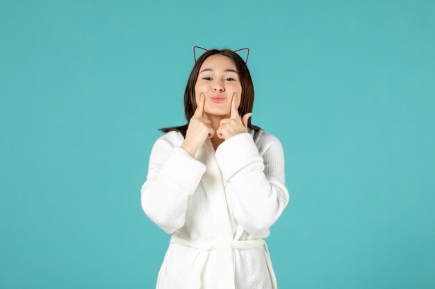 front view of young woman in bathrobe on blue wall