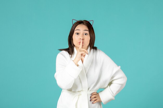 front view of young woman in bathrobe on blue wall