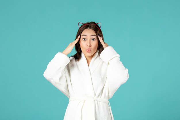 front view of young woman in bathrobe on blue wall