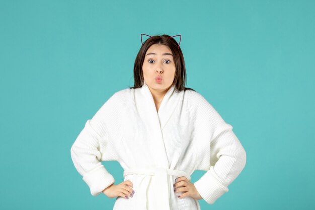 front view of young woman in bathrobe on blue wall