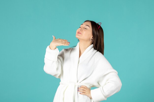 front view of young woman in bathrobe on blue wall