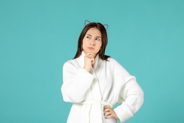 front view of young woman in bathrobe on blue wall