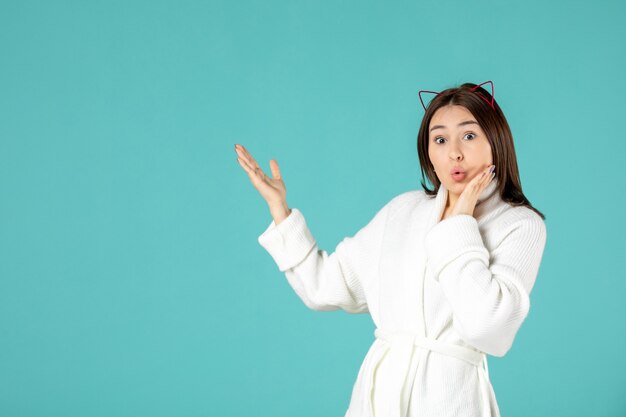 front view of young woman in bathrobe on blue wall