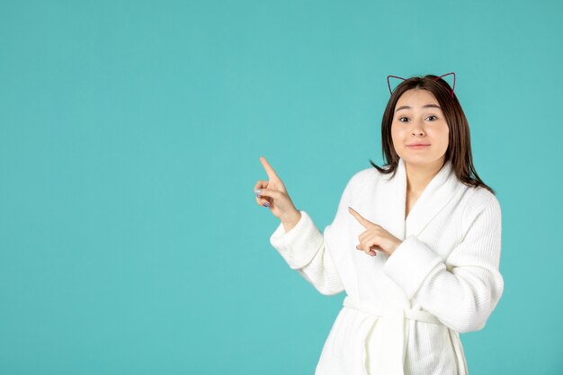 front view of young woman in bathrobe on blue wall