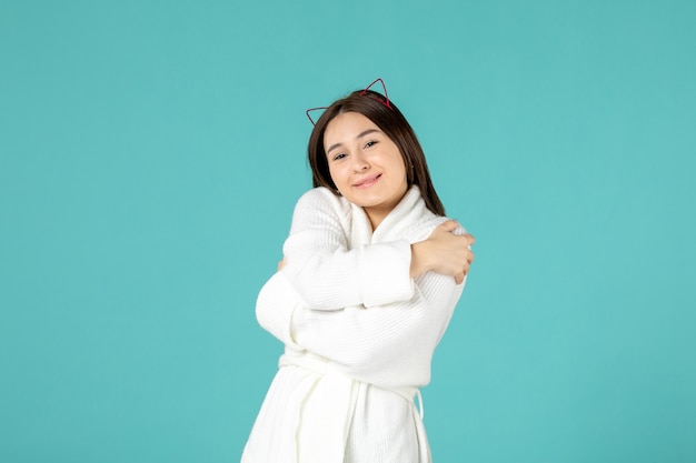 front view of young woman in bathrobe on blue wall