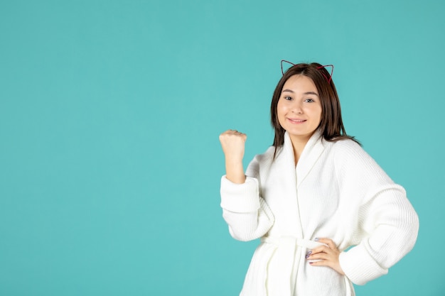 front view of young woman in bathrobe on blue wall