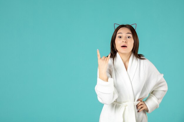 front view of young woman in bathrobe on blue wall