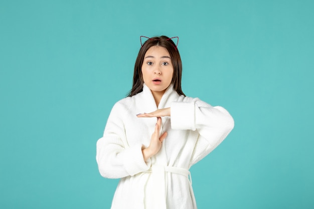 front view of young woman in bathrobe on blue wall