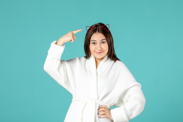 front view of young woman in bathrobe on blue wall