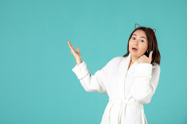 front view of young woman in bathrobe on blue wall