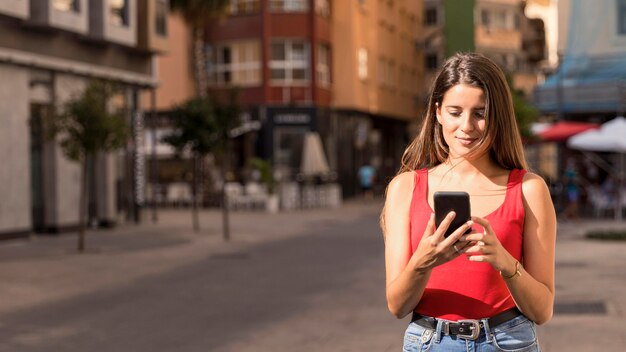 Вид спереди молодая женщина просматривает мобильный телефон