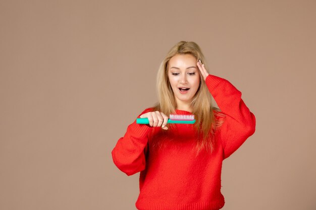 front view young woman brushing her hair on brown wall