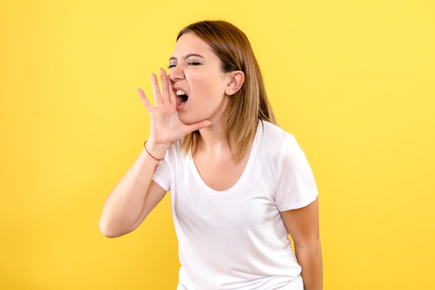Front view of young woman calling on yellow wall