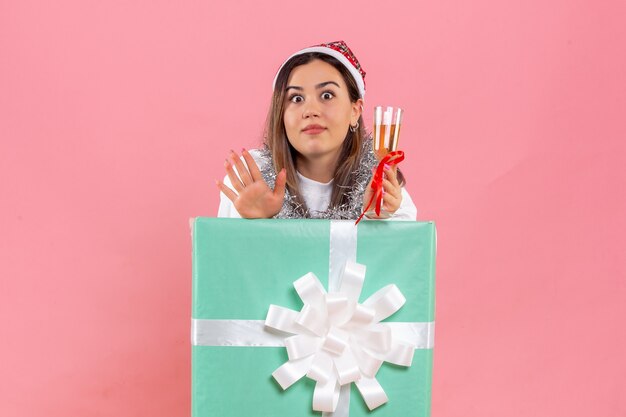 Front view of young woman celebrating xmas with drink on a pink wall