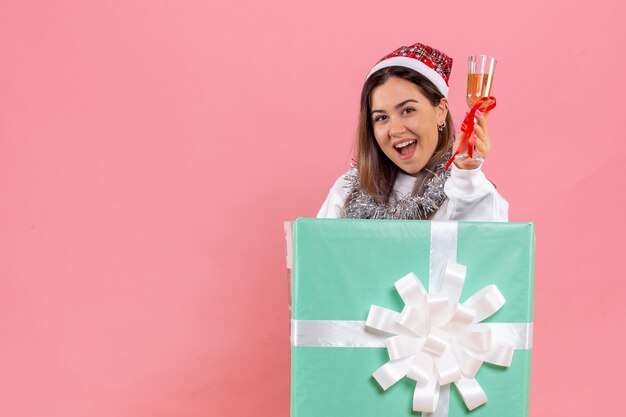 ピンクの壁に飲み物とクリスマスを祝う若い女性の正面図