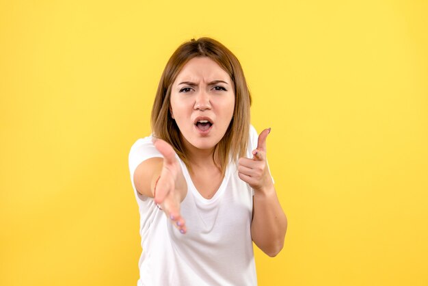 Front view of young woman confused on yellow wall