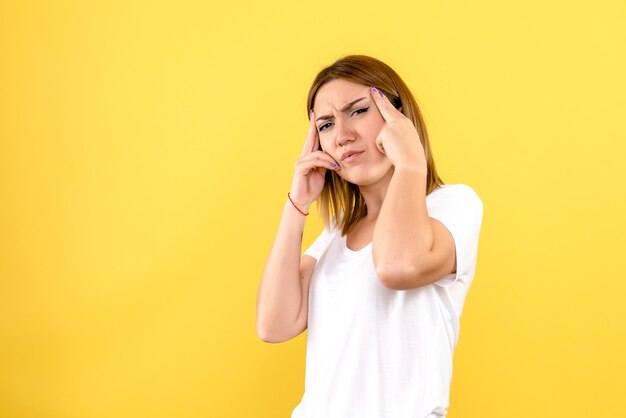 Front view of young woman confused on yellow wall