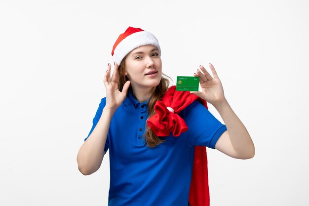 Front view of young woman courier holding bank card on white wall